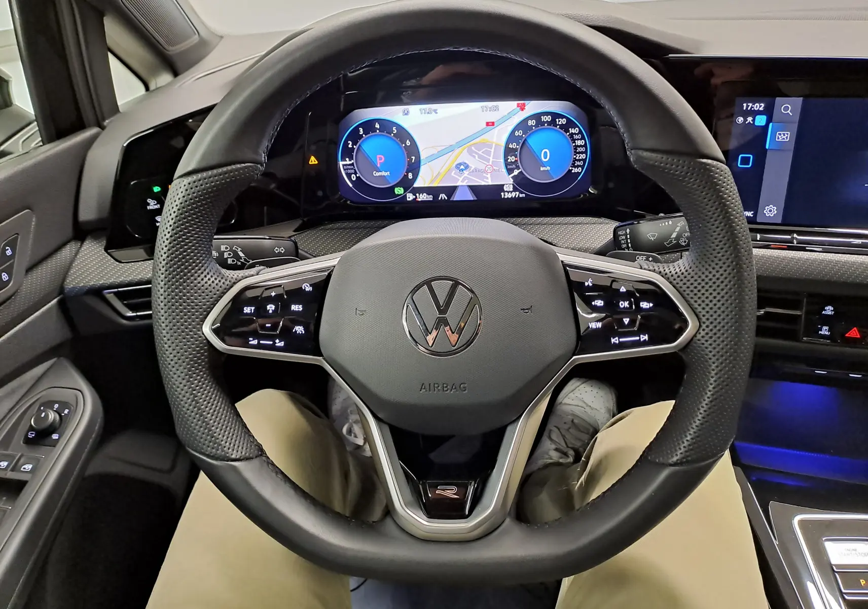 Vue intérieure centrée sur le volant cuir perforé noir avec logo VW et tableau de bord digital d'une Volkswagen Golf 2023.