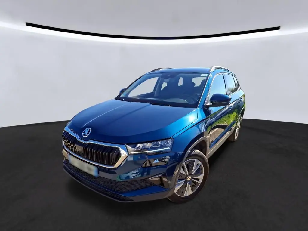 Vue 3/4 avant droite d'un Skoda Karoq bleu métallisé avec calandre chromée et jantes alu 17 pouces.