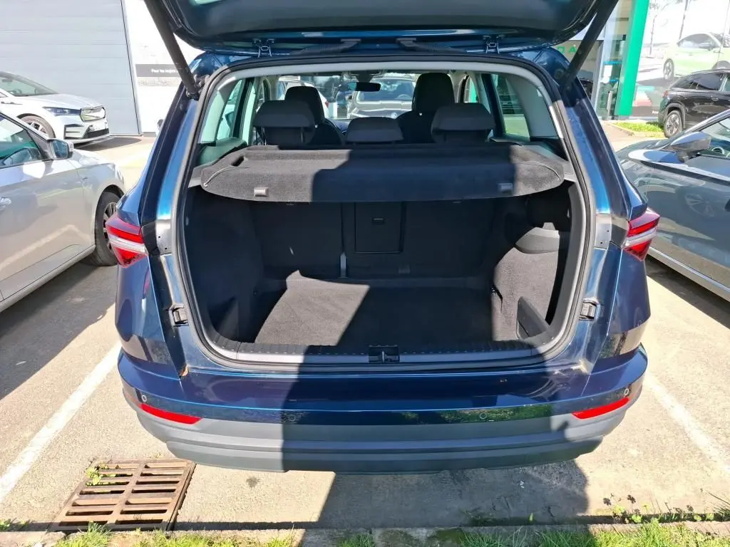 Vue arrière du coffre ouvert d'un Skoda Karoq bleu 2026, avec cache-bagages et sièges arrière visibles.