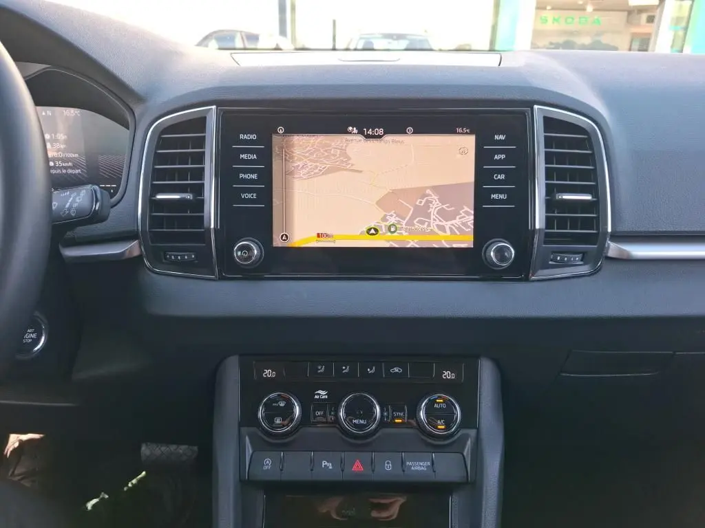 Vue intérieure centrée sur la console centrale du Skoda Karoq avec écran tactile de navigation et commandes de climatisation.