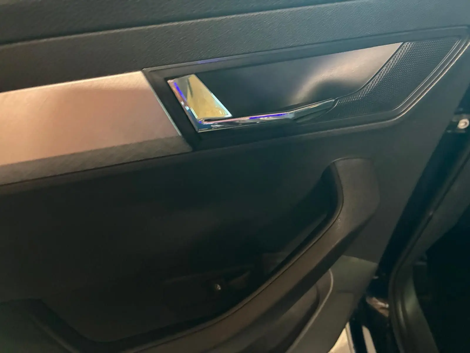 Détail de la porte intérieure côté gauche du Skoda Karoq 2023 avec poignée chromée et insert décoratif gris.