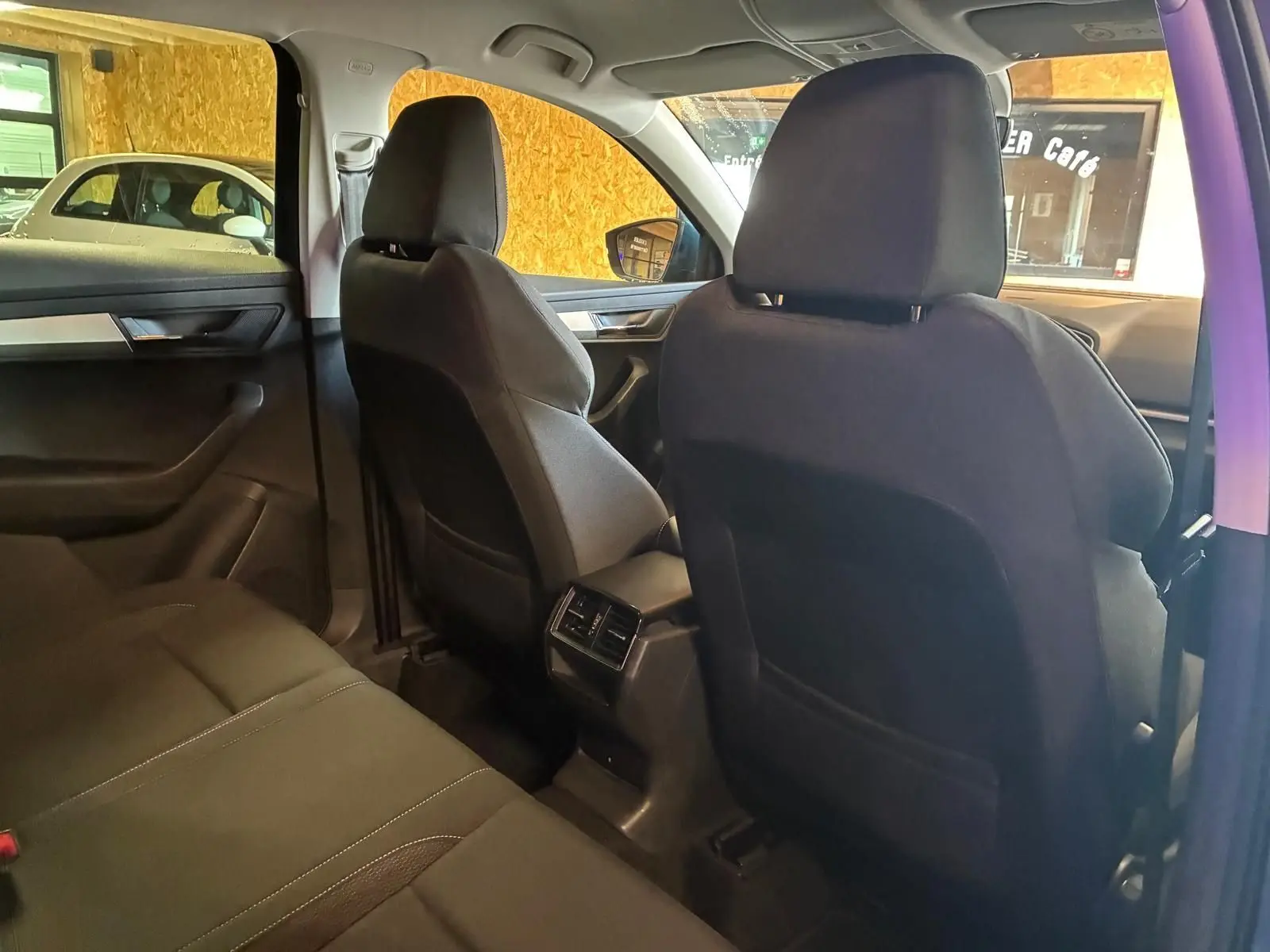 Vue intérieure arrière du Skoda Karoq bleu 2023, montrant les sièges noirs et les aérateurs centraux arrière.