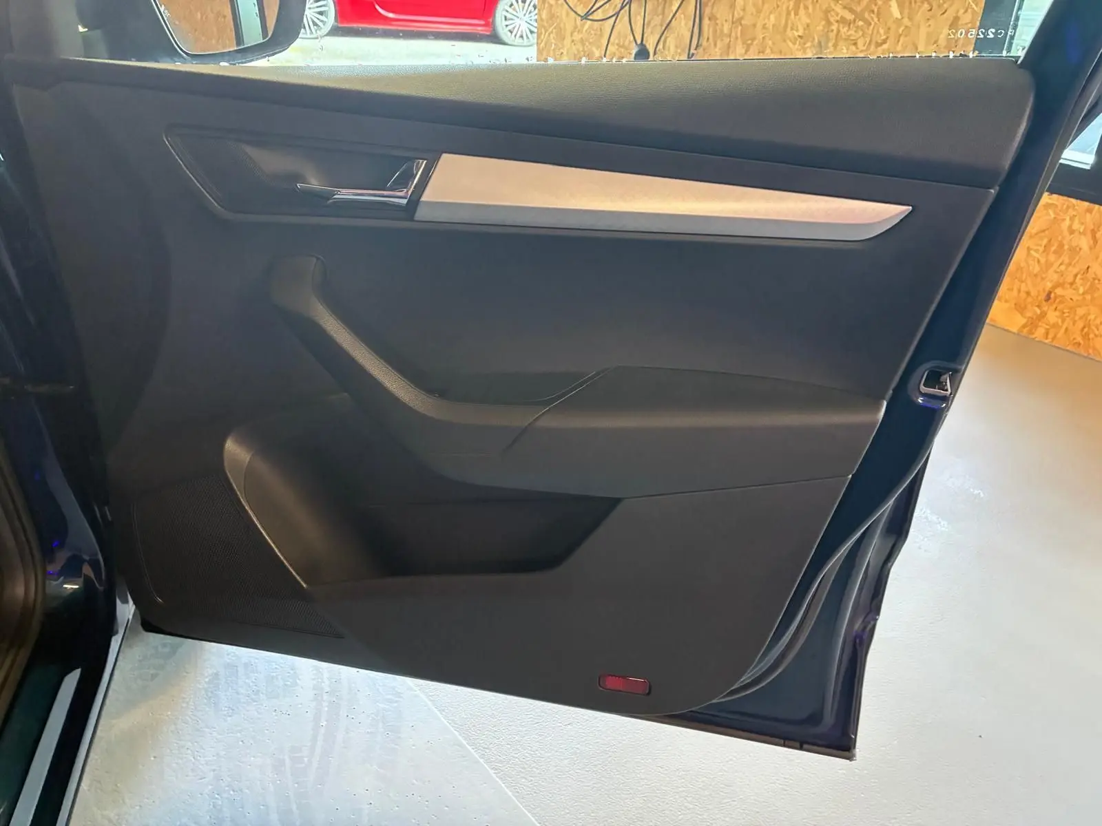 Porte arrière gauche ouverte d’un Skoda Karoq bleu 2023, intérieur noir avec insert décoratif gris clair.