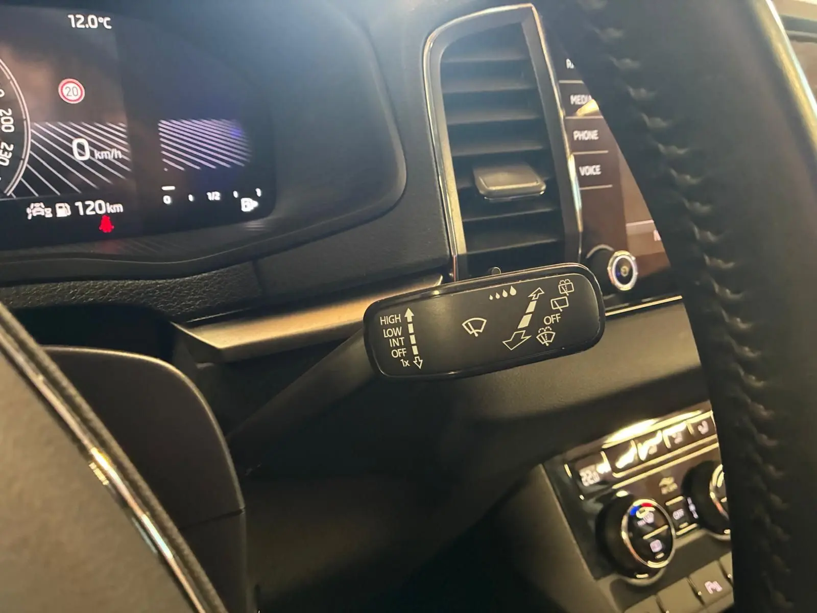Gros plan sur la commande des essuie-glaces à gauche du volant dans l'habitacle noir du Skoda Karoq 2023.