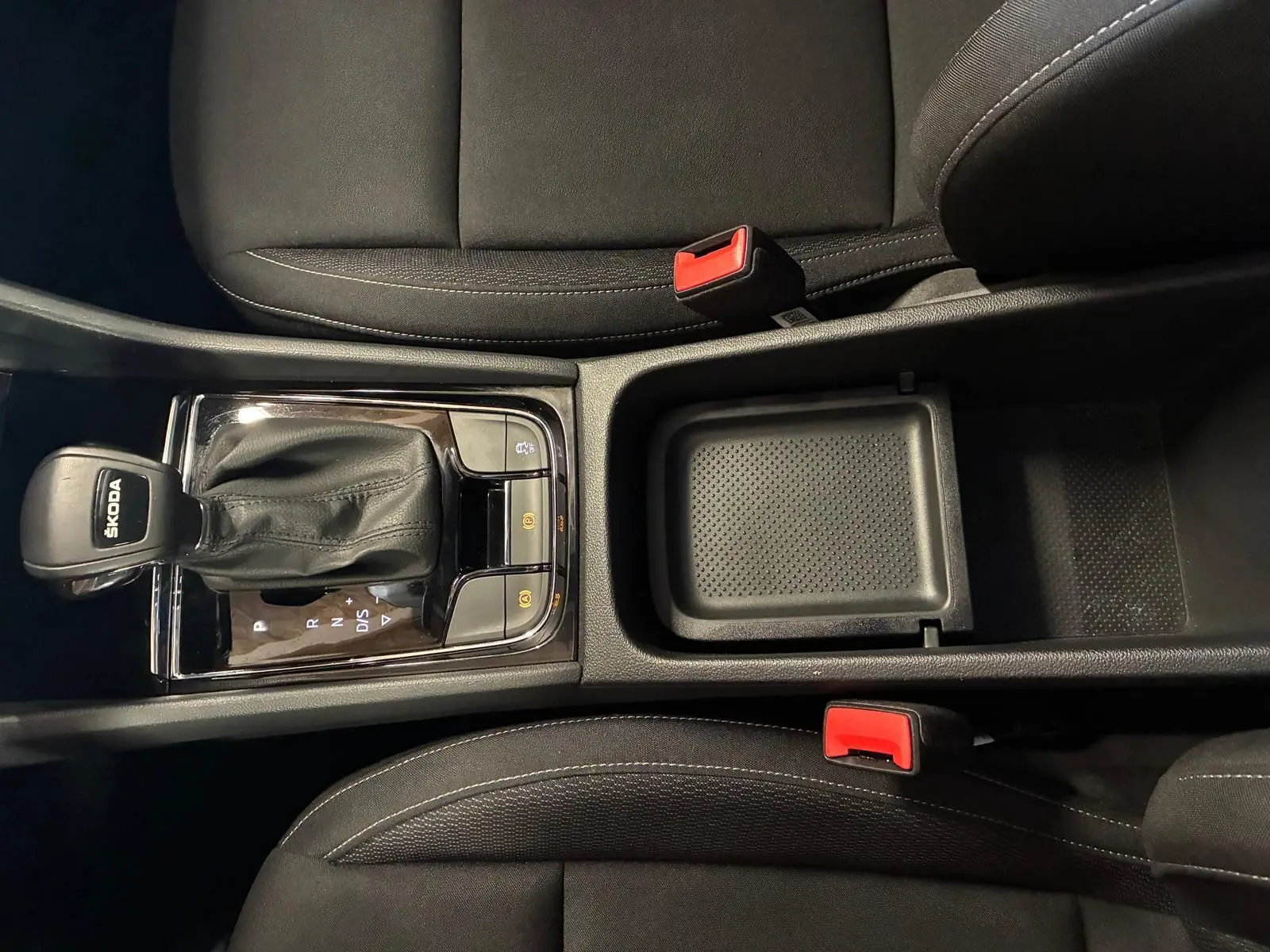 Vue plongeante sur la console centrale noire avec levier de vitesse automatique et sièges tissu noir du Skoda Karoq bleu 2023.