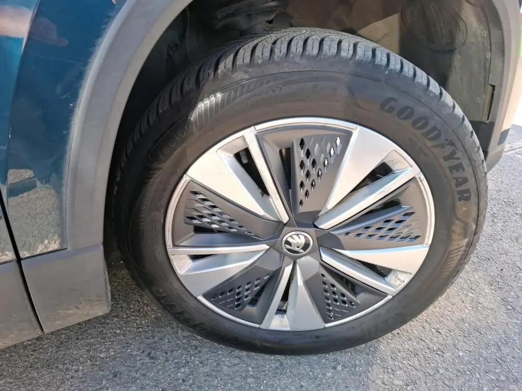 Gros plan sur la roue avant droite d'un Skoda Karoq bleu, jante alu 17 pouces avec logo central chromé.
