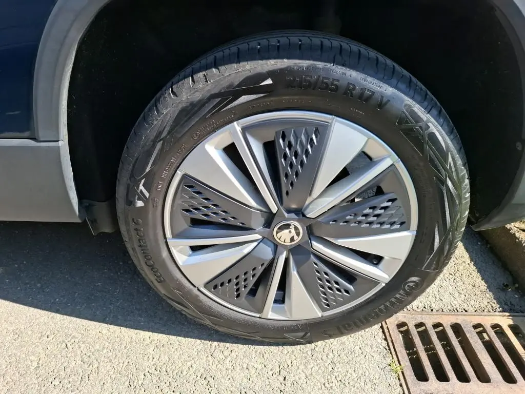 Gros plan sur la roue avant droite d’un Skoda Karoq bleu avec jante alu 17 pouces au design moderne.