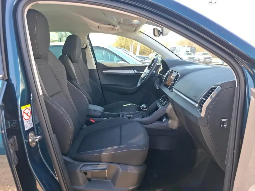 Vue intérieure côté conducteur d'un Skoda Karoq bleu 2026, montrant sièges noirs et tableau de bord moderne.