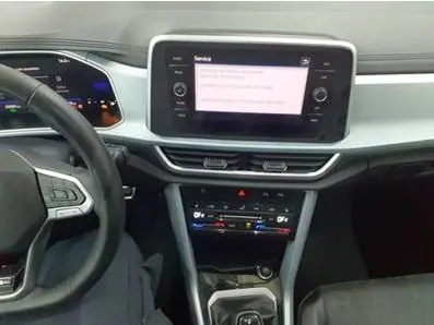 Vue intérieure du tableau de bord du Volkswagen T-Roc 2025 gris foncé, avec écran tactile central et commandes climatisation.