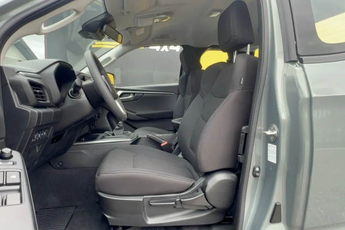 Vue intérieure côté conducteur du pick-up Isuzu D-MAX 2026 vert Inishmore, sièges tissu noir et tableau de bord visible.