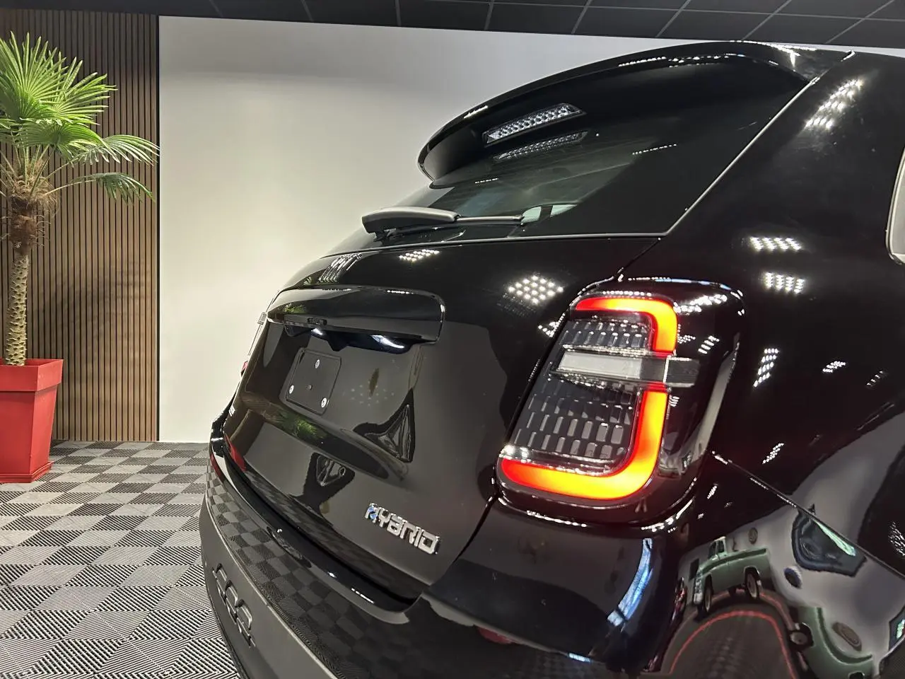 Vue 3/4 arrière droite d'une Fiat 600 noire hybride avec feux arrière LED et logo Hybrid sur hayon.
