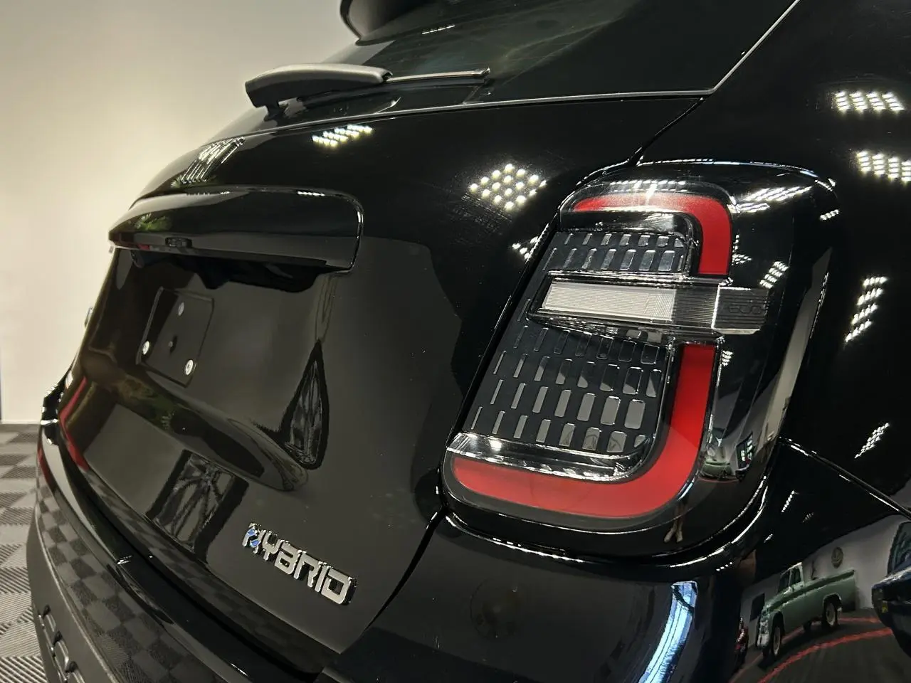 Vue 3/4 arrière droite d'une FIAT 600 noire avec feux arrière LED et logo Hybrid sur le hayon.