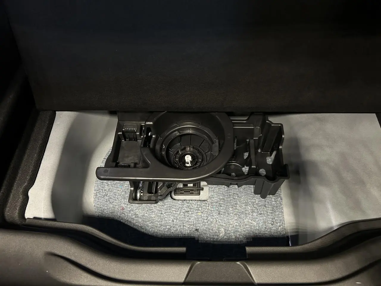 Vue rapprochée du coffre ouvert d’une Fiat 600 noire, montrant le rangement sous plancher avec support d’outils intégré.