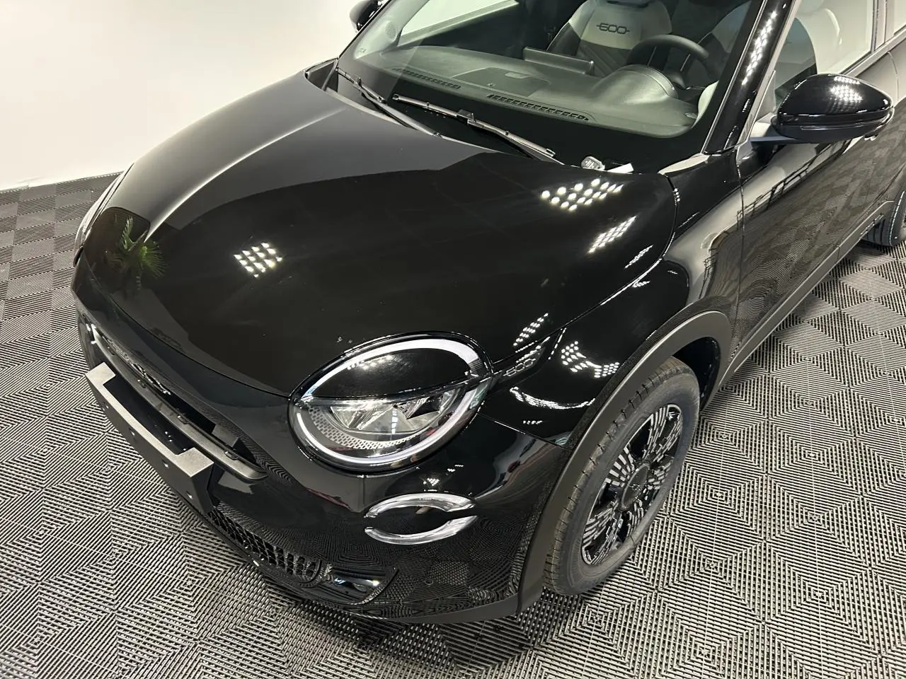 Vue 3/4 avant droite d'une FIAT 600 noire avec phares LED ronds et jantes alliage noires au design complexe.