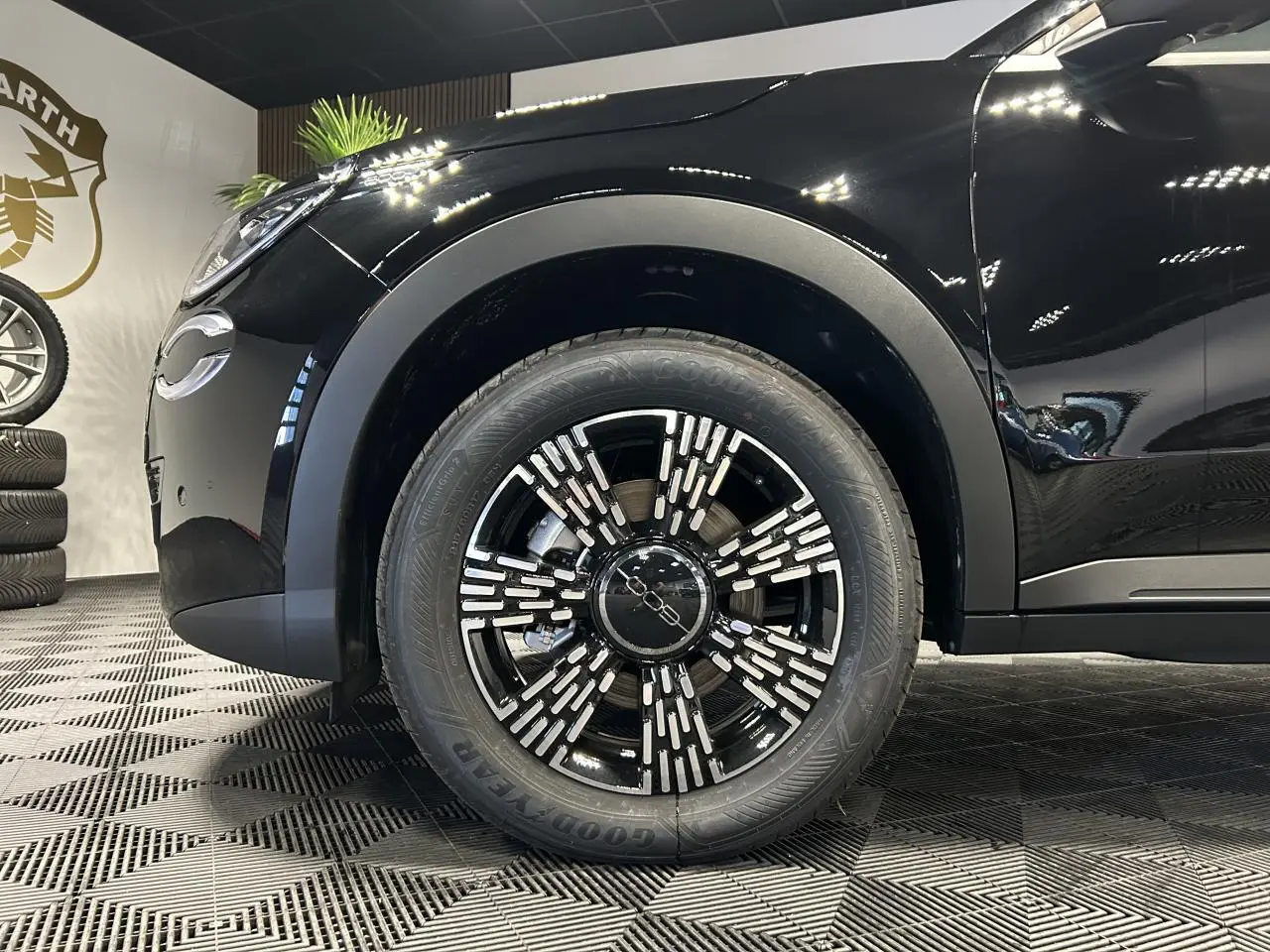 Gros plan sur la roue avant gauche noire du FIAT 600 hybride, avec jante alliage noire et détails argentés.
