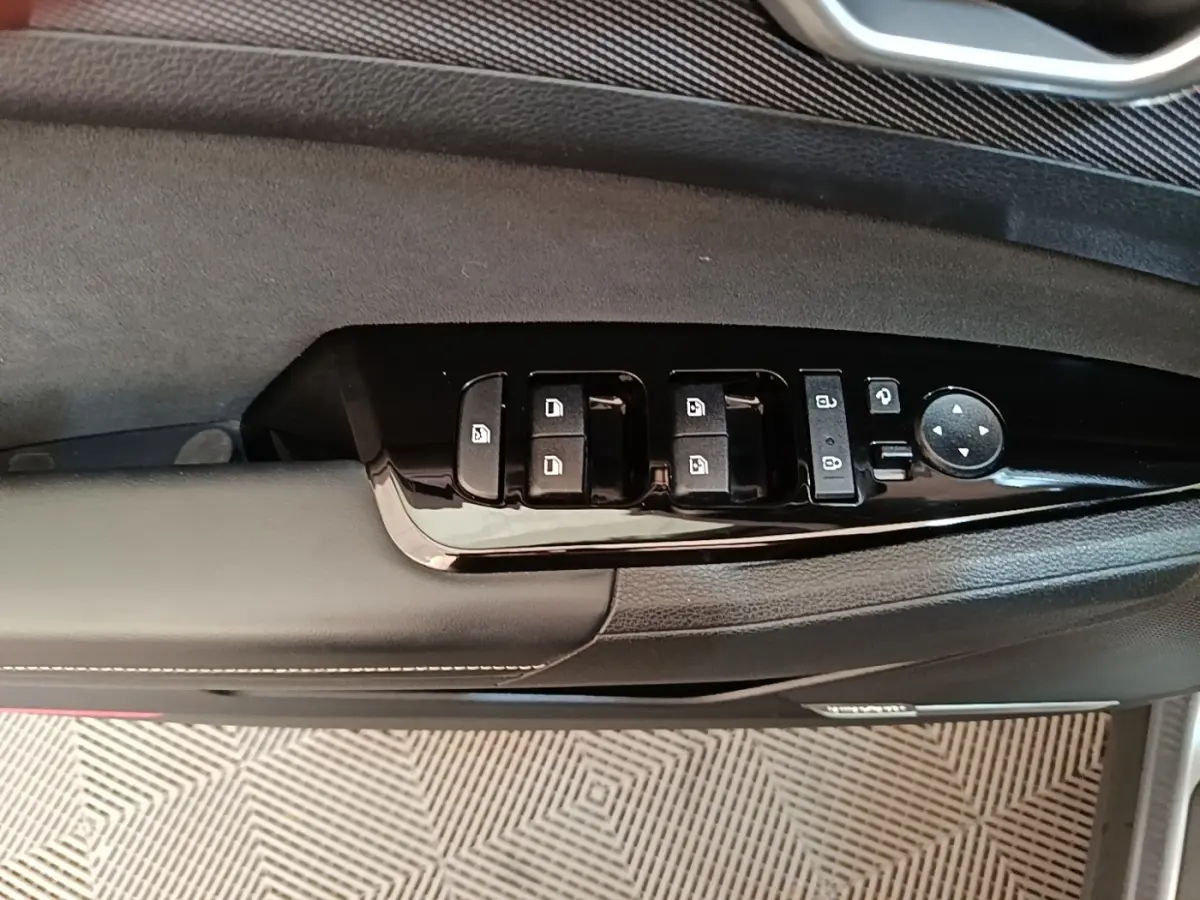 Gros plan sur la commande des vitres et rétroviseurs côté gauche d'une porte intérieure noire du Kia Sportage gris clair 2022.