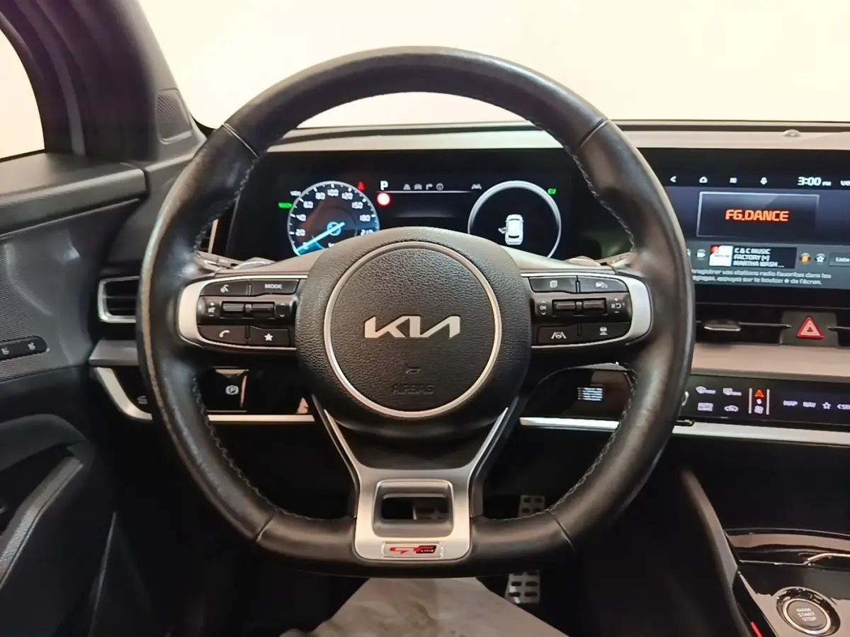 Vue intérieure centrée sur le volant cuir KIA GT-L avec tableau de bord digital et écran tactile 12,3 pouces.