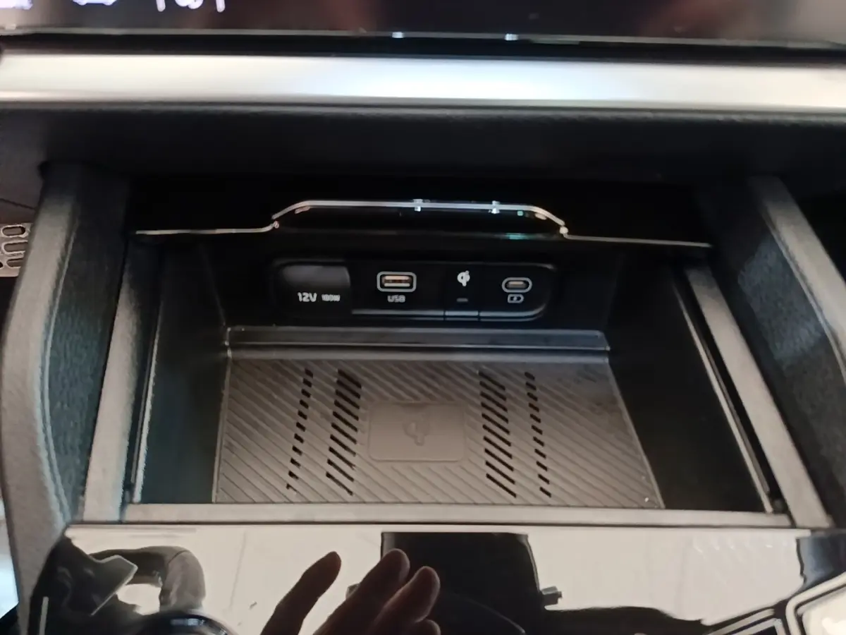 Gros plan sur la console centrale du Kia Sportage 2022, montrant les prises USB, 12V et recharge sans fil.