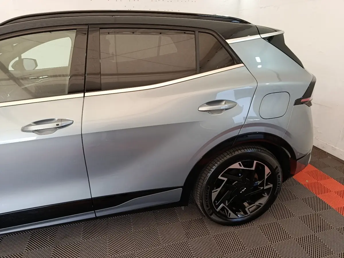 Vue côté droit arrière du Kia Sportage gris clair hybride rechargeable avec jantes noires au design moderne.