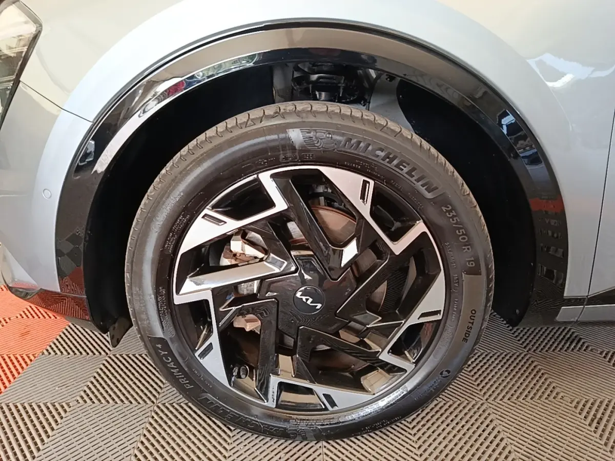 Gros plan sur la roue avant droite du Kia Sportage gris clair 2022 avec jante noire et argentée au design géométrique.