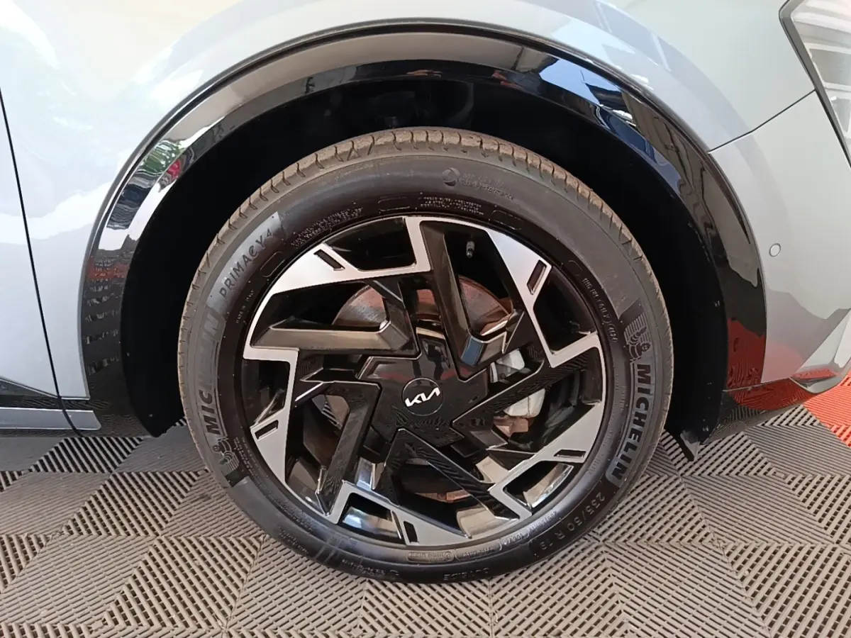 Gros plan sur la roue avant gauche grise du Kia Sportage 2022 avec jante noire et argent au design géométrique.