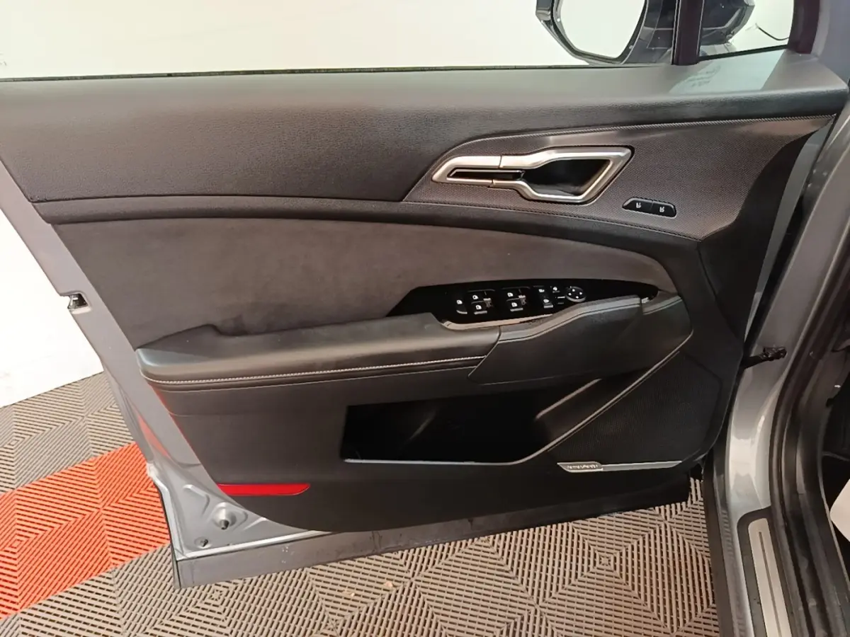 Vue intérieure de la porte avant gauche gris clair du Kia Sportage avec commandes électriques et garniture noire.