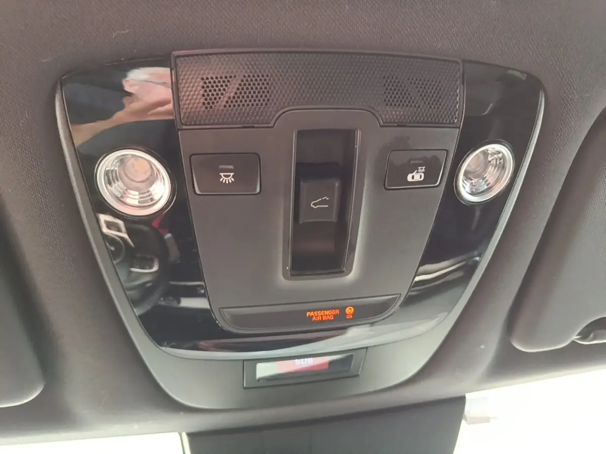 Vue intérieure du plafonnier noir brillant du Kia Sportage 2022 avec commandes d’éclairage et indicateur airbag passager.