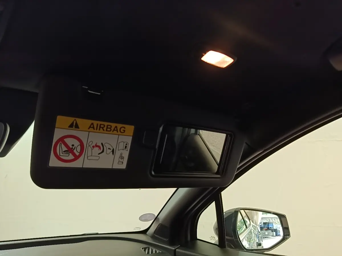Intérieur du Kia Sportage 2022, vue côté passager avec pare-soleil ouvert et miroir intégré, éclairage intérieur allumé.
