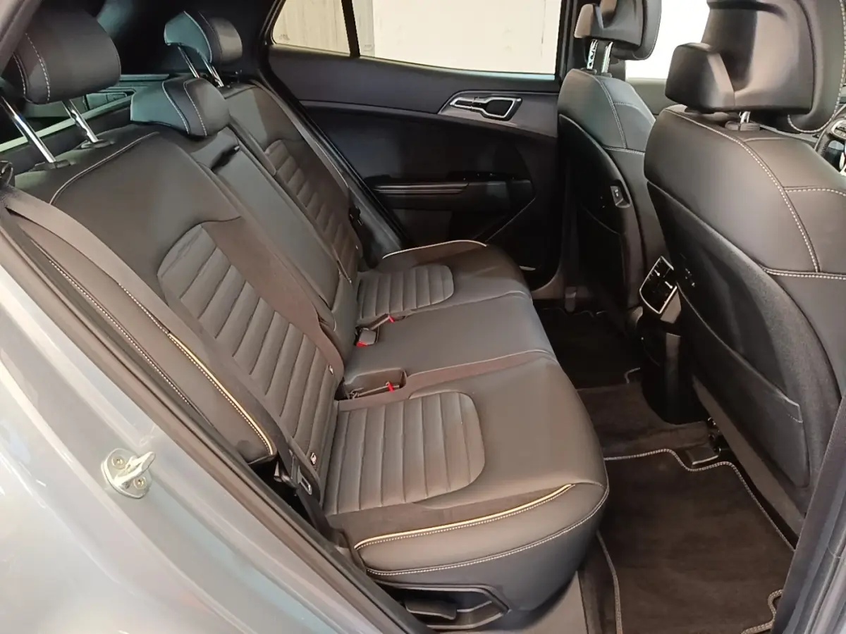 Vue côté gauche des sièges arrière en cuir noir avec surpiqûres blanches d'un KIA Sportage gris clair 2022.