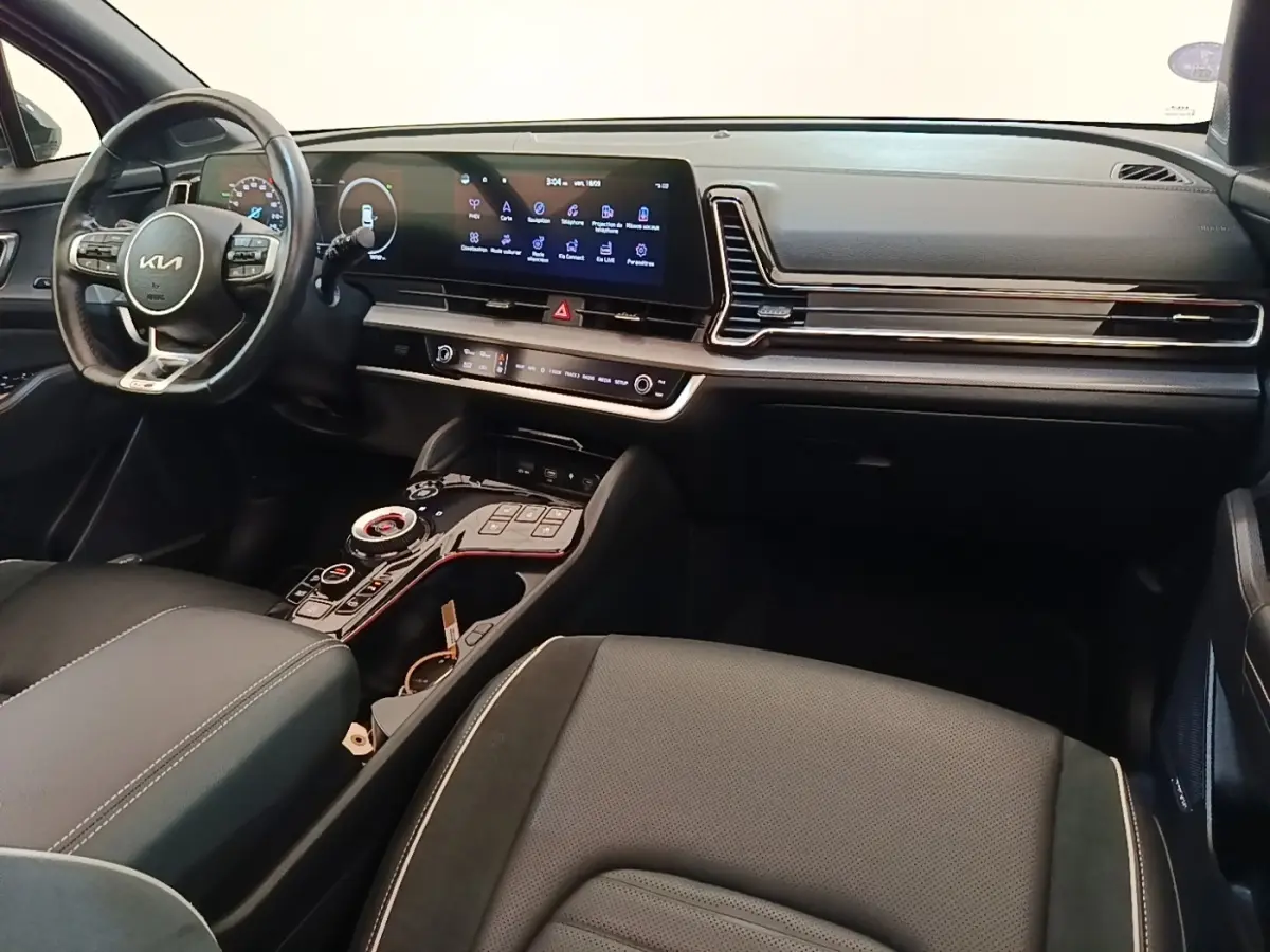 Intérieur du Kia Sportage 2022 vu côté conducteur, tableau de bord noir avec écran tactile large et volant multifonctions.