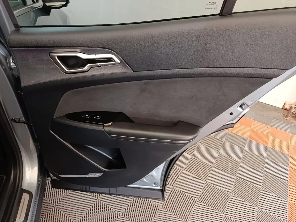Vue intérieure de la porte arrière gauche gris clair du Kia Sportage 2022 avec garniture noire et commandes de fenêtre.