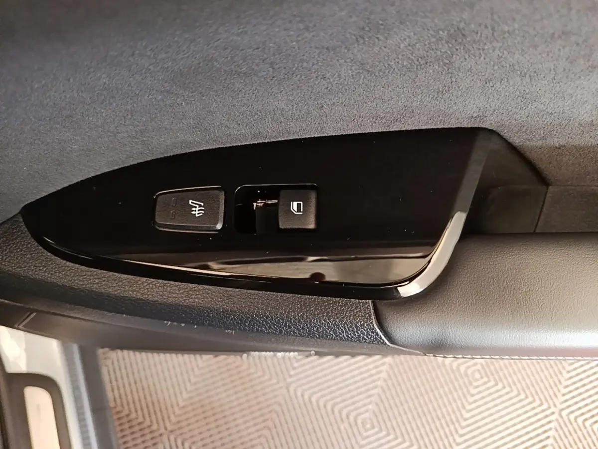 Détail des commandes de siège chauffant et verrouillage sur la porte côté conducteur d’un KIA Sportage gris clair.