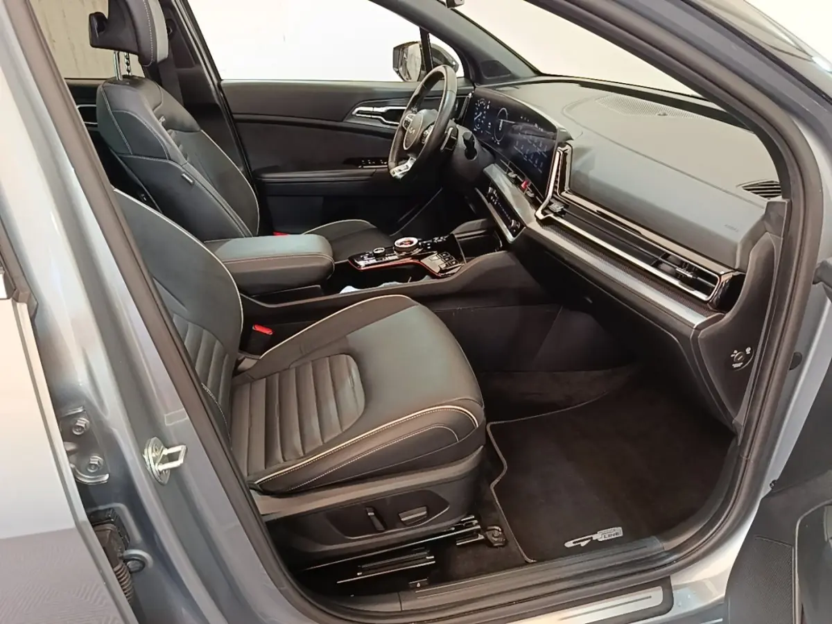 Intérieur avant du Kia Sportage gris clair 2022, vue côté droit, sièges cuir noirs et tableau de bord digital large.