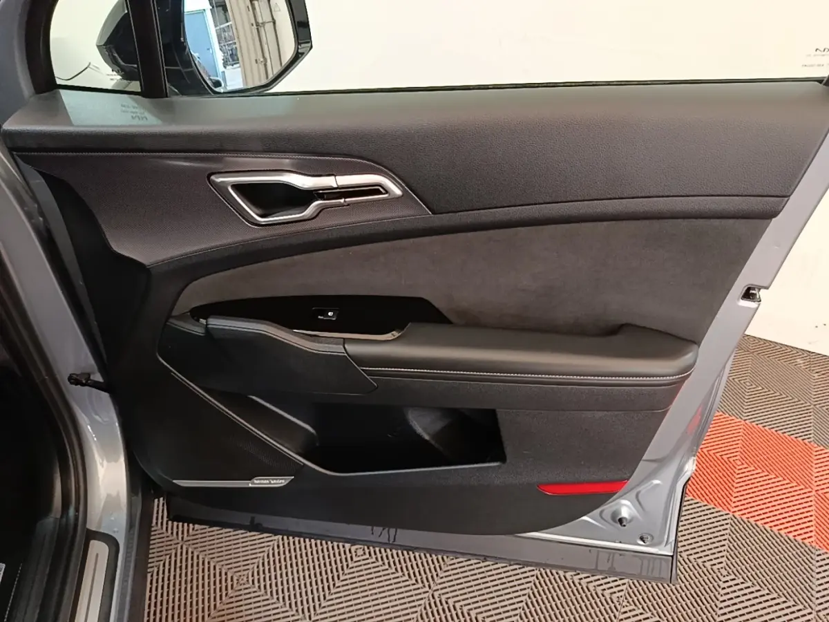 Vue intérieure côté gauche de la porte avant grise du Kia Sportage 2022 avec garniture noire et insert Harman Kardon.