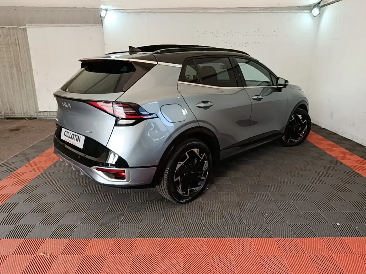 Vue 3/4 arrière droite du KIA Sportage gris clair hybride rechargeable avec toit noir et jantes noires stylisées.