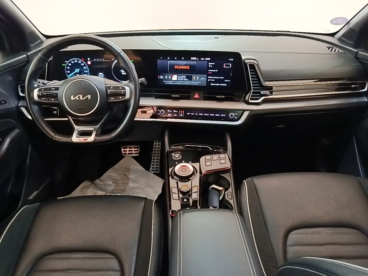 Vue intérieure du tableau de bord et volant noir du Kia Sportage 2022 avec écran tactile large et console centrale moderne.