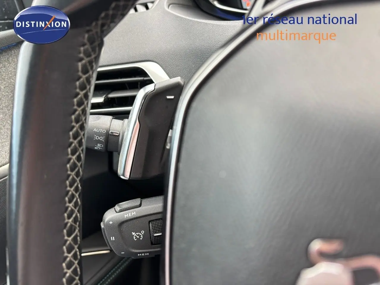 Gros plan sur le volant et les commandes à gauche du tableau de bord du Peugeot 3008 bleu Celebes Hybrid 2022.