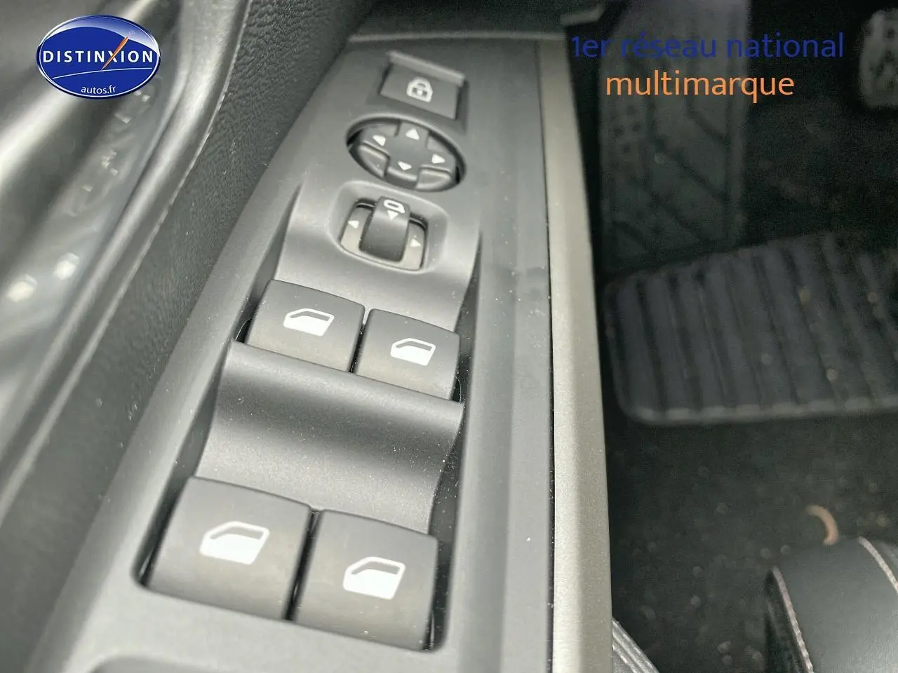 Gros plan sur les commandes des vitres électriques côté conducteur du Peugeot 3008 bleu 2025.