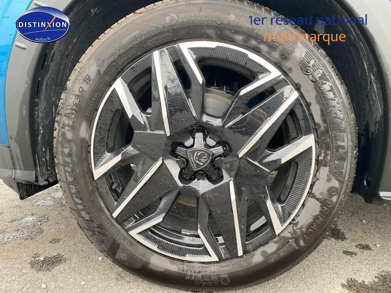 Gros plan sur la jante alu noire et argentée d’un Peugeot 3008 bleu, vue côté droit sous la roue avant.