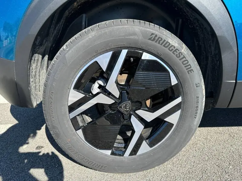 Gros plan sur la roue avant droite du Peugeot 2008 1.2 Hybrid Bleu Obsession avec jante noire et argentée au design moderne.