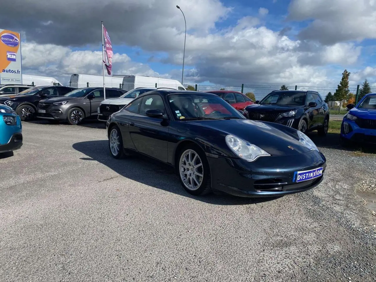 Porsche 911 Targa gris foncé vue en 3/4 avant droit sur un parking avec jantes sport et toit fermé.