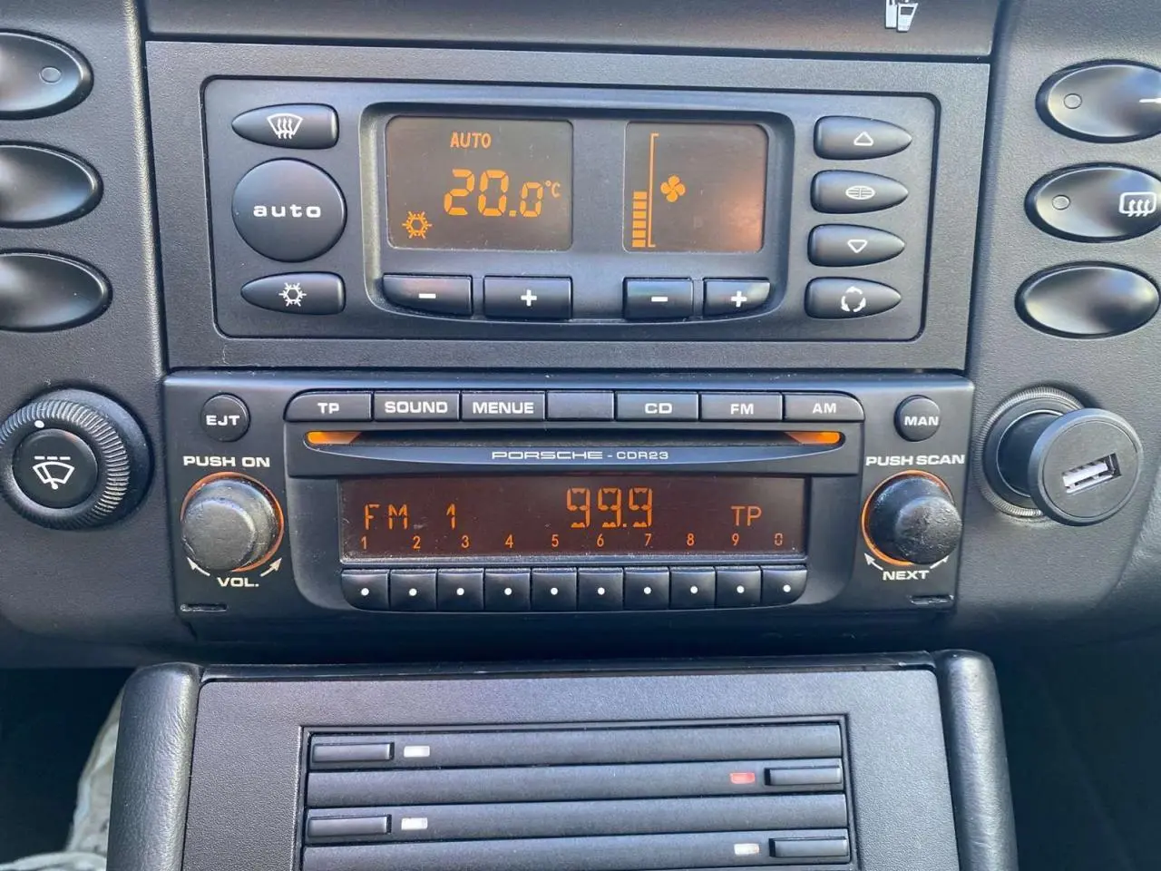 Détail de la console centrale de la Porsche 911 Targa 996 grise, affichant la climatisation et l’autoradio d’origine.