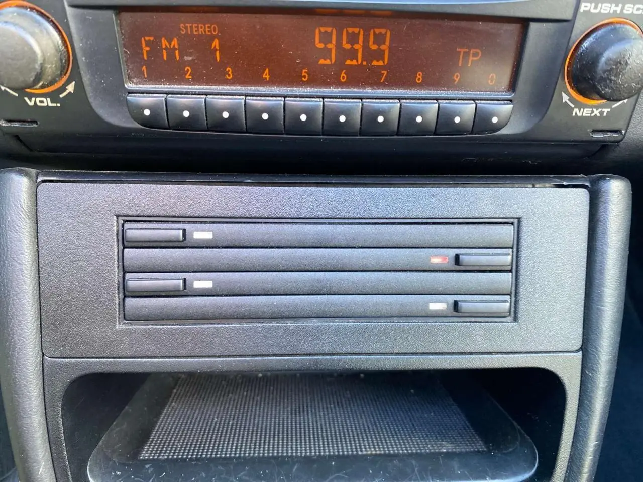 Gros plan sur la radio et le lecteur CD de la Porsche 911 Targa 996 gris foncé, intérieur cuir visible en arrière-plan.