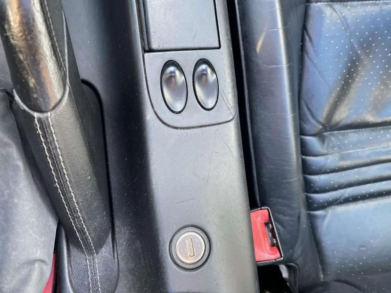 Gros plan sur la console centrale en cuir noir du Porsche 911 Targa 996 avec levier de frein à main et boutons de commande.