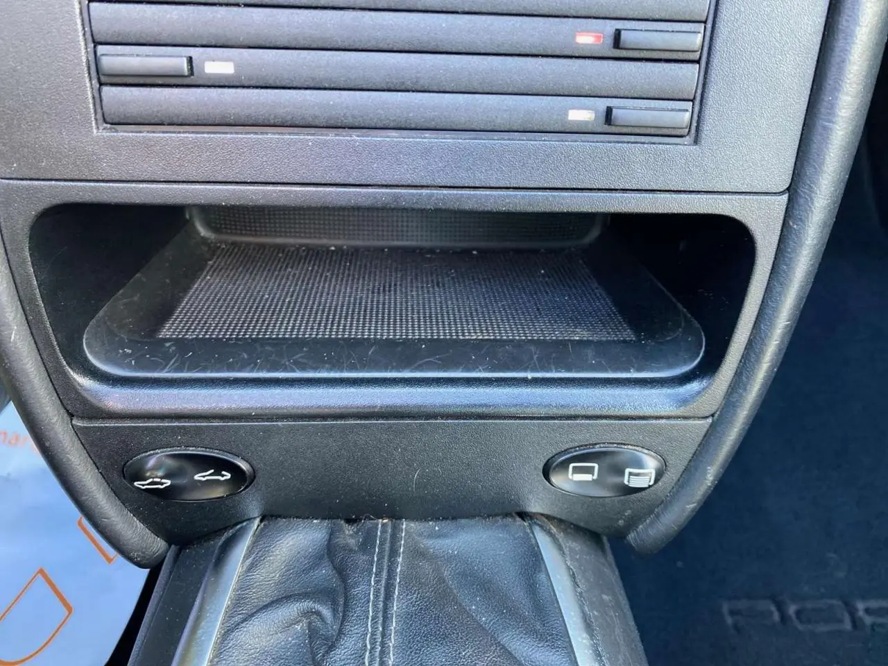Gros plan sur la console centrale en cuir noir du Porsche 911 Targa 996, avec levier de vitesse et commandes d'ouverture des coffres.
