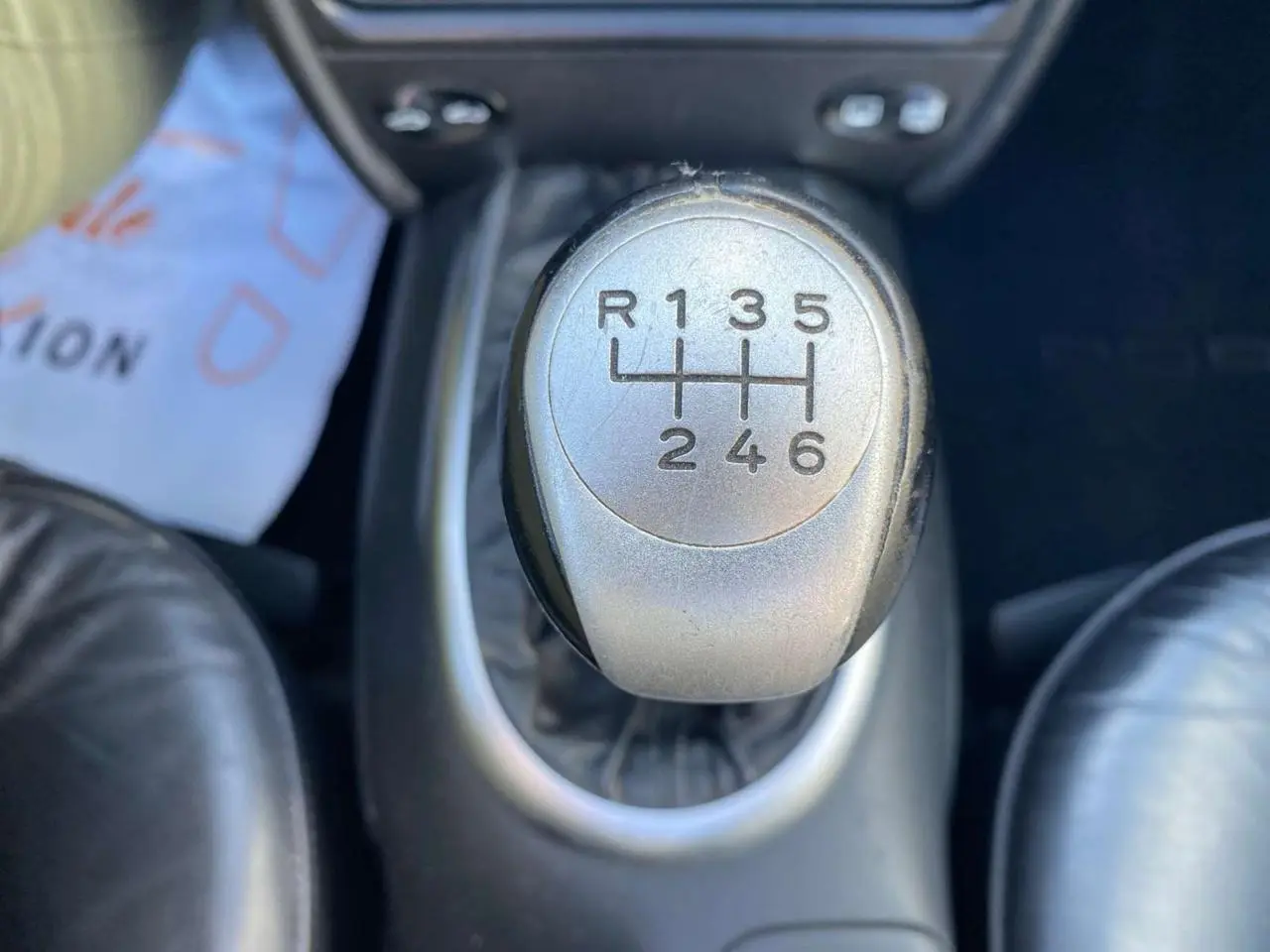 Gros plan sur le levier de vitesse manuel en alu et cuir de la Porsche 911 Targa gris foncé, intérieur cuir visible.