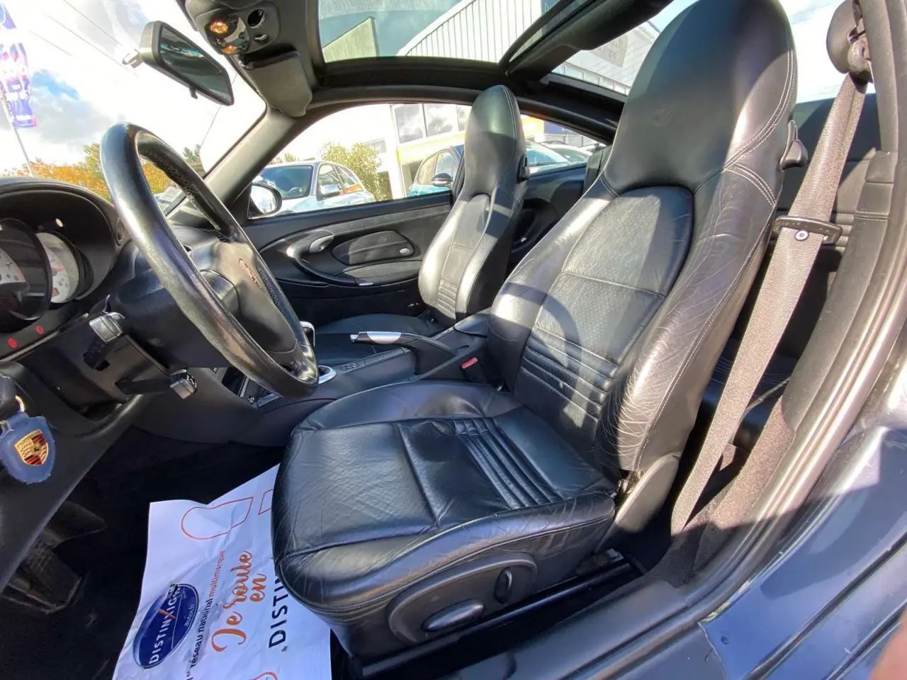 Vue intérieure côté conducteur de la Porsche 911 Targa gris foncé, sièges cuir noirs et levier de vitesse alu-cuir visible.