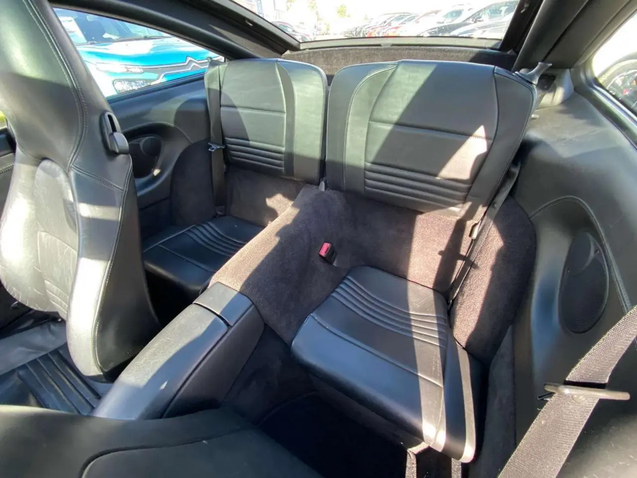 Vue intérieure arrière montrant les sièges arrière en cuir noir du Porsche 911 Targa gris foncé de 2004.