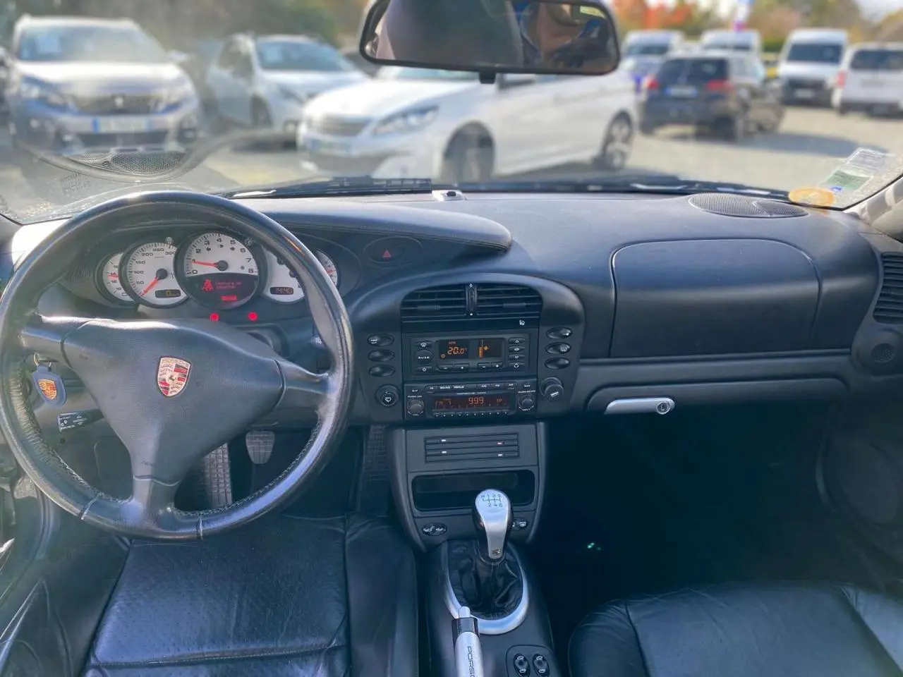 Vue intérieure avant de la Porsche 911 Targa gris foncé, avec volant cuir, tableau de bord et levier de vitesse alu-cuir.