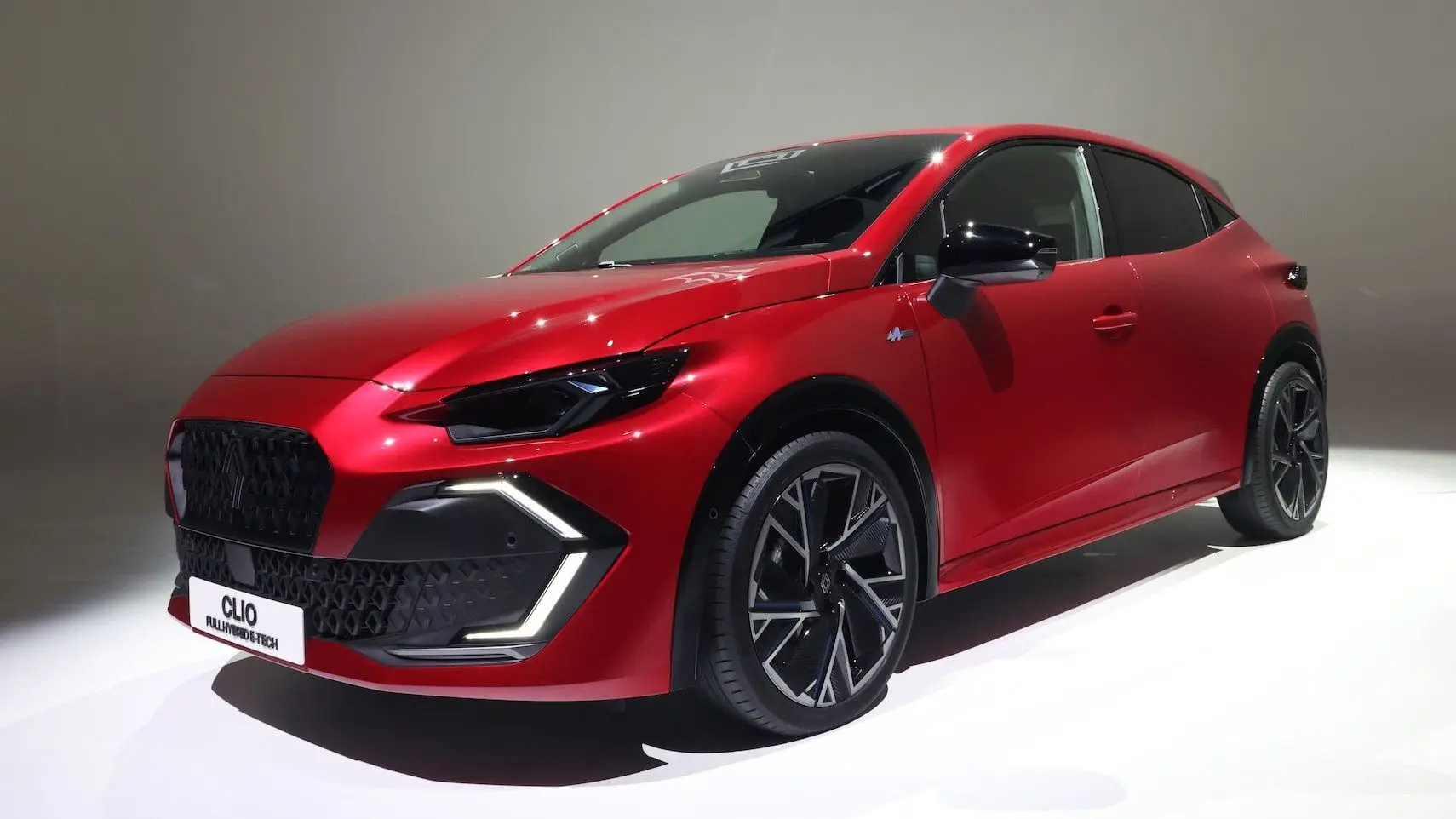 Renault Clio VI TCe 115ch Techno rouge vue 3/4 avant droit avec feux LED en forme de C et jantes noires.